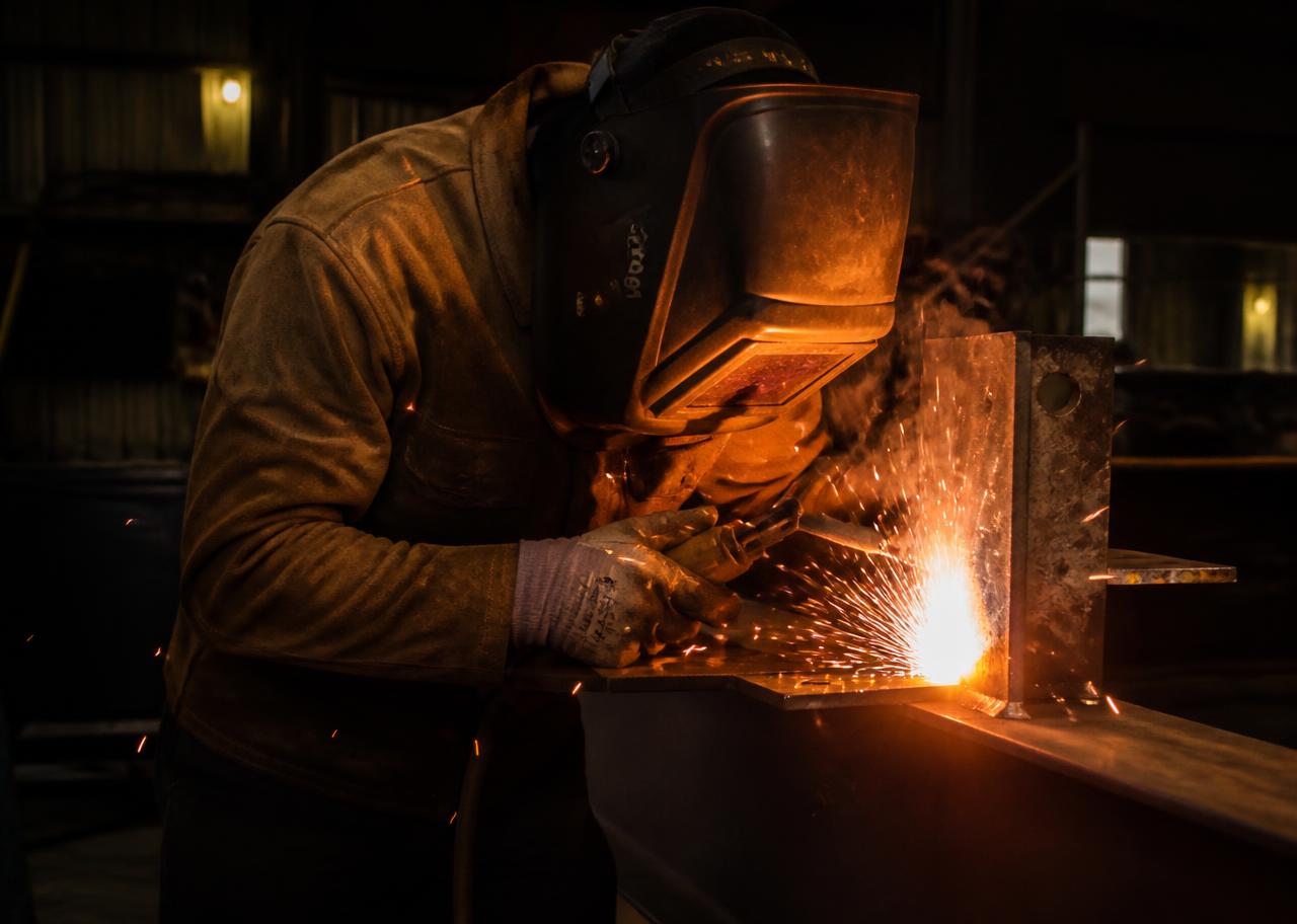 Welder striking an arc on structural steel with bright sparks
